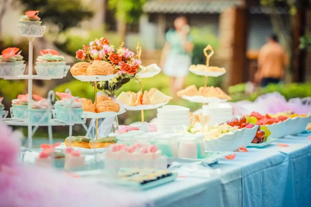 Table set with sweets on various stands and decorated with white tablecloth and flowers