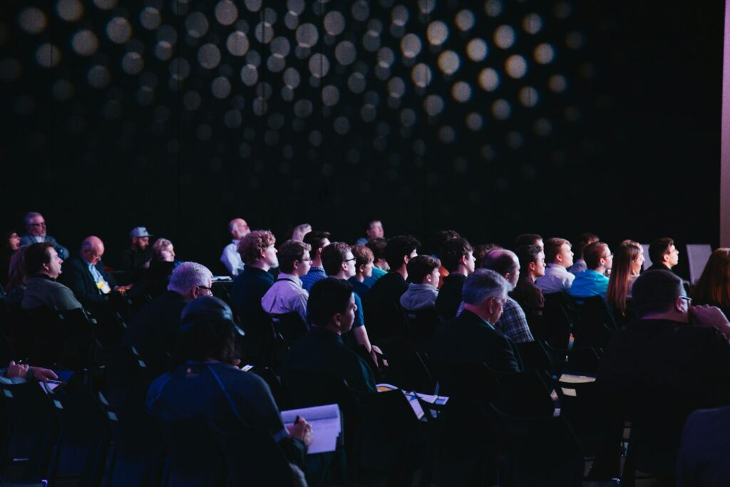 Conference attendees seated in an auditorium listening to a keynote session