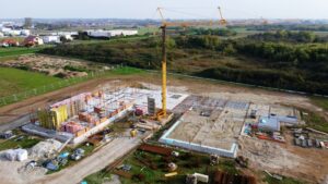 Aerial drone photo of a construction site with a tower crane, foundations and staged materials